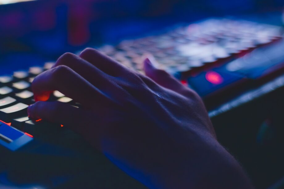 Main tapant sur un clavier retroeclaire dans la penombre, illustrant la ligne de commande comme primitive des agents IA